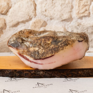 Pancetta tesa di suino nero dei Nebrodi con superficie pepata su tagliere